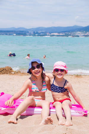 little girls playing on a sandy beach and sunbathe in the sunの写真素材