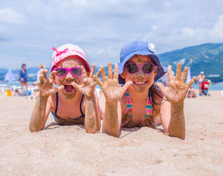 little girls playing on a sandy beach and sunbathe in the sunの写真素材