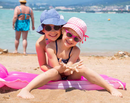little girls playing on a sandy beach and sunbathe in the sunの写真素材
