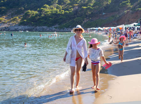 young woman with two children walking on sandy beach on the sea coastの写真素材