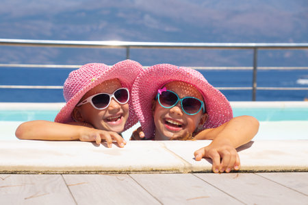 Two little girls play and swim in pool on resortの写真素材