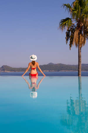 Young woman in bikini relaxing near the pool on sea resortの写真素材