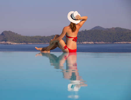Young woman in bikini relaxing near the pool on sea resortの写真素材