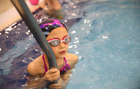 little girl swimming in the pool at the training in swimmingの写真素材