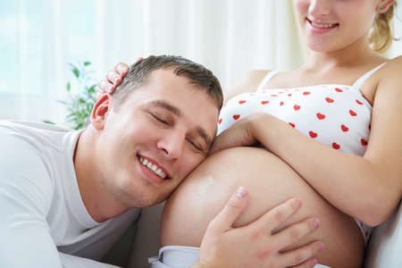 Happy husband holding belly his pregnant wifeの写真素材