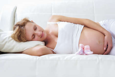 Pregnant woman relaxing on sofa at homeの写真素材