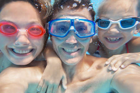 underwater photo of little boy with his family swimming in poolの写真素材