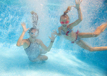 underwater photo of young mother with little girl in swimming poolの写真素材