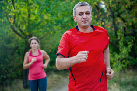 Pair of elderly people jogging on a summer dayの写真素材