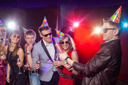 Cheerful young people showered with confetti on a club party.の写真素材