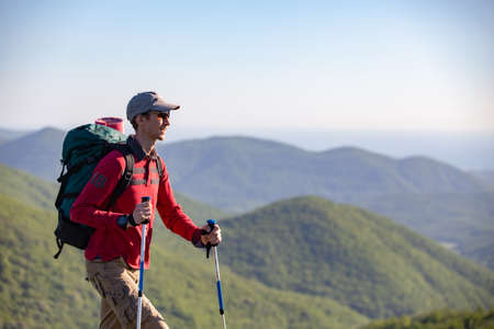 tourist with sticks goes on a hike through the mountainsの写真素材