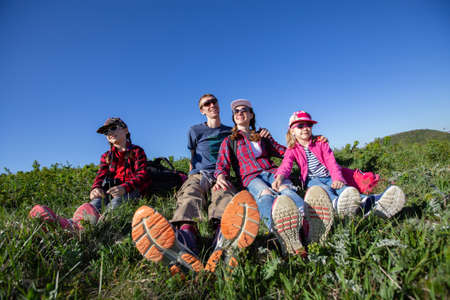 Family with two children resting on a meadow in a hike through mountainsの写真素材