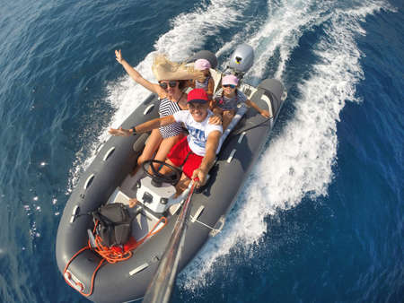 family with children sailing on an inflatable motorboat in the seaの写真素材