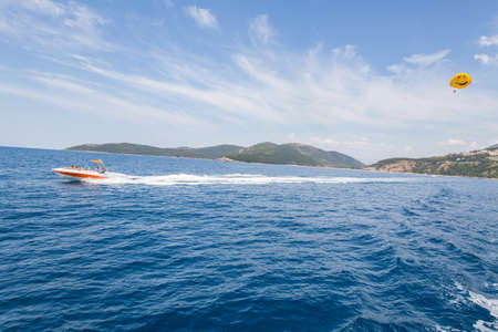 motor boat rides a paraglider on a long rope with a lover of extreme relaxation at sea.の写真素材