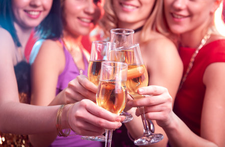 Beautiful girls clink glasses of champagne at a partyの写真素材