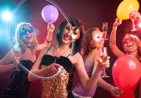 Dance happy young girls under masks on the partyの写真素材