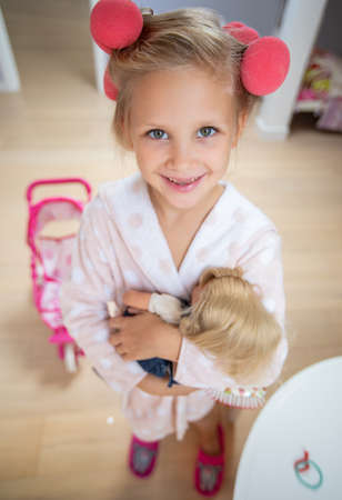 portrait of little cute ladies playing with doll in children's roomの写真素材