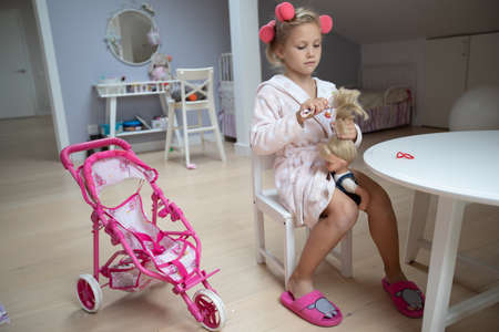 portrait of little cute ladies playing with doll in children's roomの写真素材