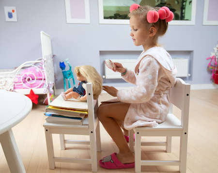 portrait of little cute ladies playing with doll in children's roomの写真素材