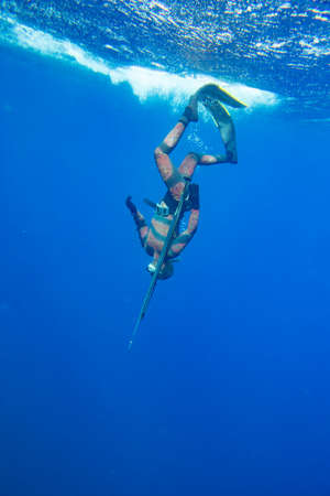 Underwater hunter with gun dives into the depths of the seaの写真素材