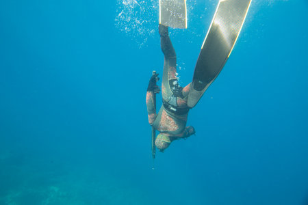 Underwater hunter with gun dives into the depths of the seaの写真素材