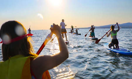 young people riding on sup surfing in the seaの写真素材