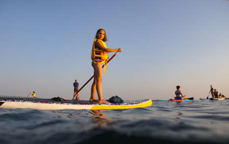 young girl riding on sup surfing in the seaの写真素材