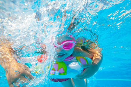Cheerful little girl swiming under water in pool.の写真素材