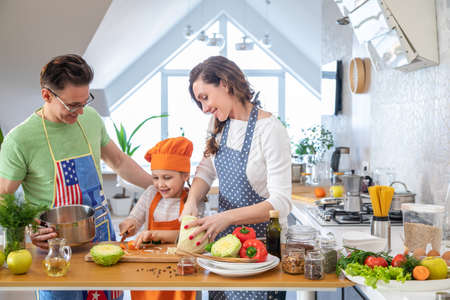 Family with young child cooking together in the kitchen at homeの写真素材