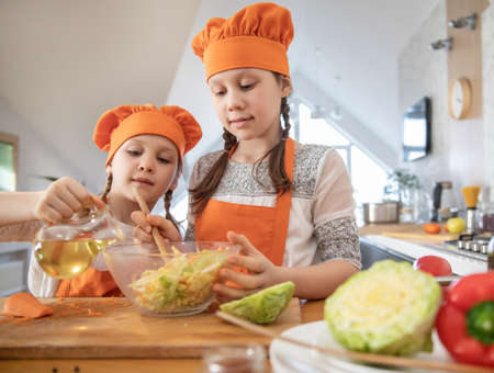 Two little girls cooking in the kitchen at homeの写真素材