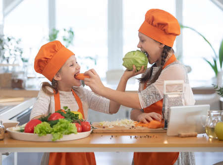 Two little girls cooking in the kitchen at homeの写真素材