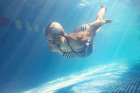 Beautiful pregnant woman dives in a pool with blue water. Underwater photography.の写真素材