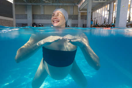 pregnant woman relaxes in a pool of blue water. Underwater photo.の写真素材