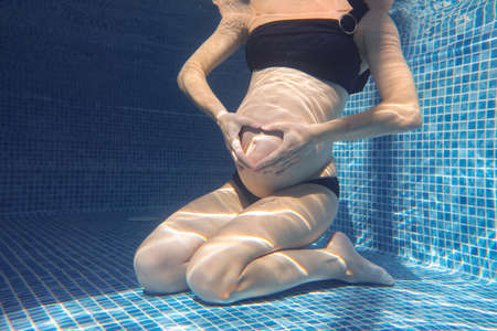 pregnant woman relaxes in a pool of blue water. Unrecognizable body.の写真素材