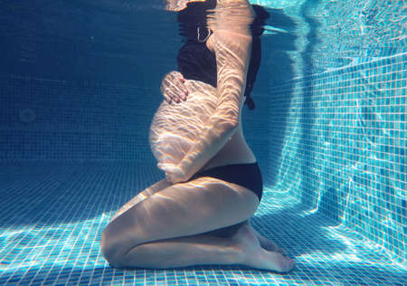 pregnant woman relaxes in a pool of blue water. Unrecognizable body.の写真素材