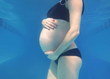 pregnant woman relaxes in a pool of blue water. Unrecognizable body.の写真素材