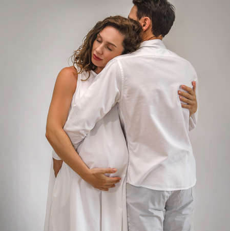 young man hugs his pregnant wife. The family is waiting for the birth of a baby.の写真素材