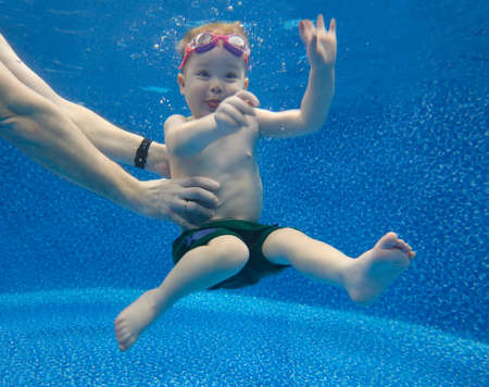Baby boy dives underwater in the pool with pleasureの写真素材