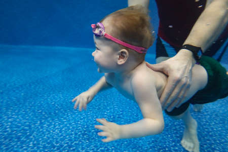Baby boy dives underwater in the pool with pleasureの写真素材