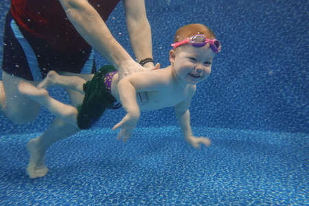 Baby boy dives underwater in the pool with pleasureの写真素材