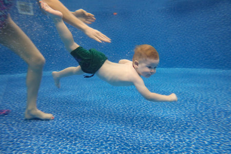 Baby boy dives underwater in the pool with pleasureの写真素材