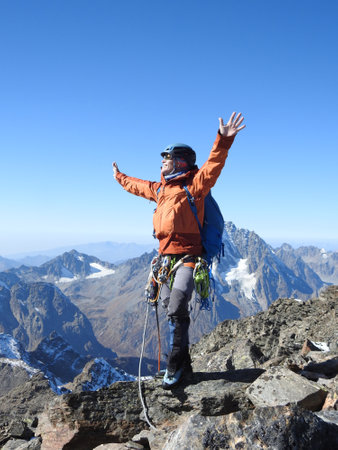 mountaineer with ice ax stands on the top of a mountain in the background of the landscape of snowy mountainsの写真素材