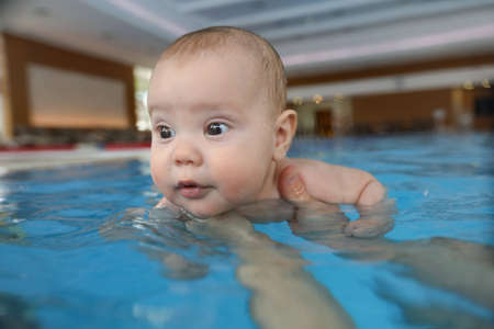 portrait of little baby girl swimming in swimming poolの写真素材