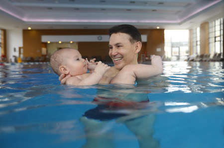 Six month old baby boy with father at his first swimming lessonの写真素材