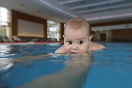 portrait of little baby girl swimming in swimming poolの写真素材
