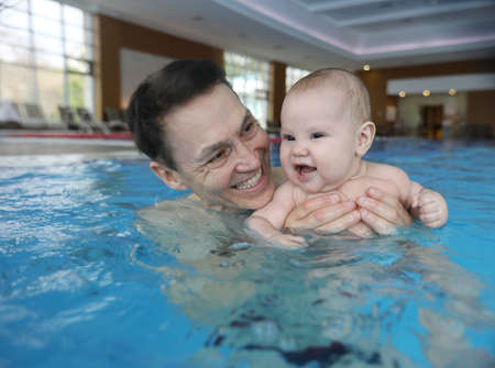 Six month old baby boy with father at his first swimming lessonの写真素材