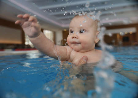 portrait of little baby girl swimming in swimming poolの写真素材
