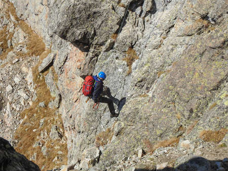 man mountaineer with ice ax climbs on the rock in mountainsの写真素材
