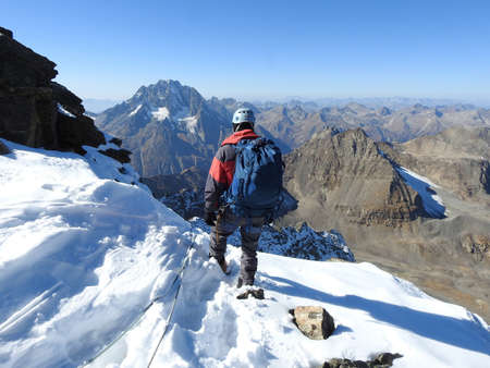 man mountaineer with ice ax climbs on the rock in mountainsの写真素材