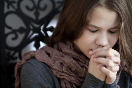 beautiful young woman crossed her fingers at the person in prayer at the churchの写真素材